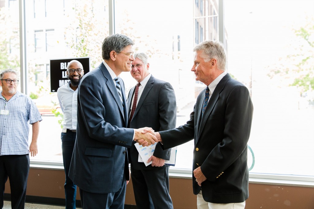 MMCDC founder Arlen Kangas shakes hands with Sec. Lew. President Kevin Shipley in background along with Seward Co-Op store manager Ray Williams.